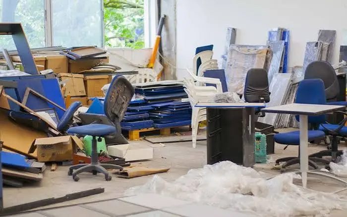 Commercial room with leftover chairs, tables, shelving panels and boxes