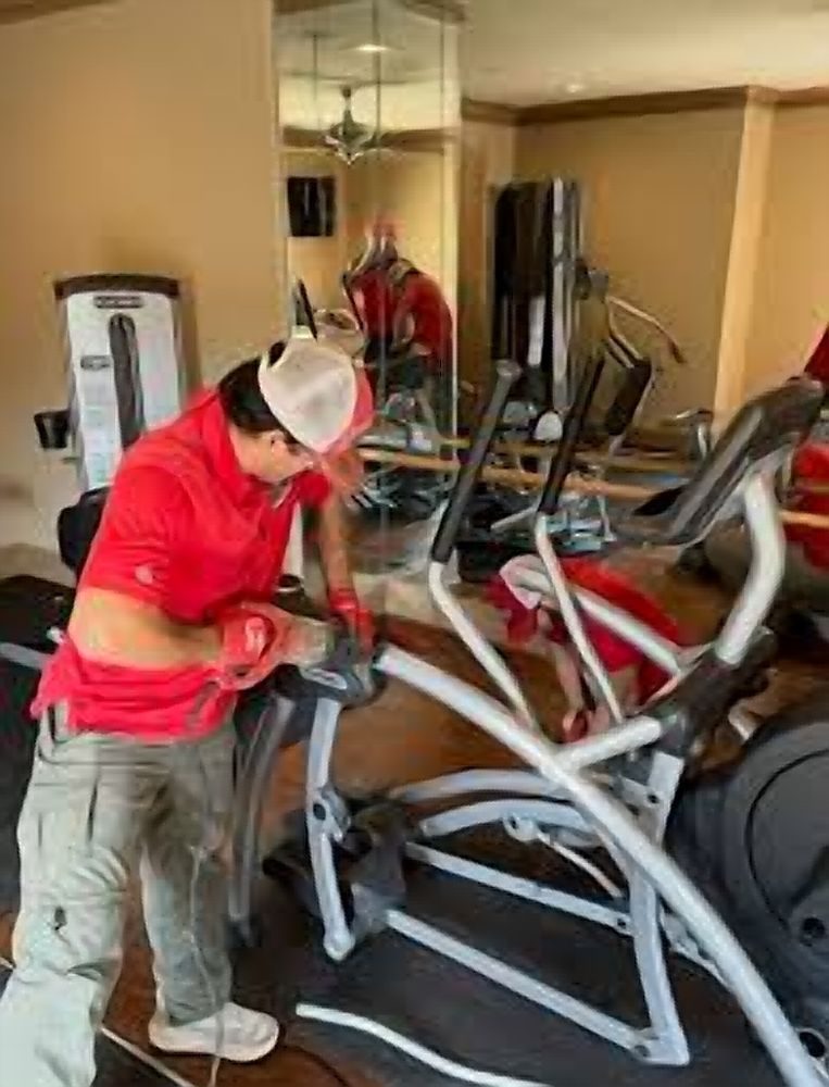 Crew member preparing an elliptical machine for removal in a home gym