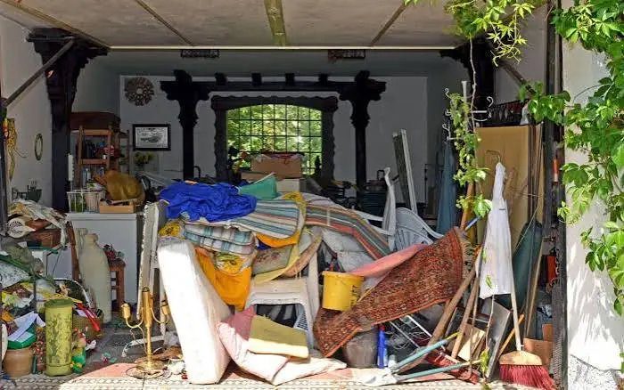 Room piled high with old mattresses, rugs, chairs and household clutter